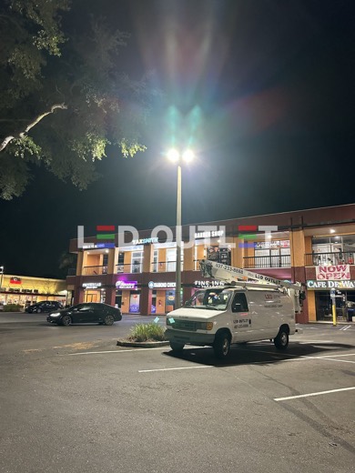 LED OUTLET bucket truck under a new LED pole light at a plaza, Orlando FL