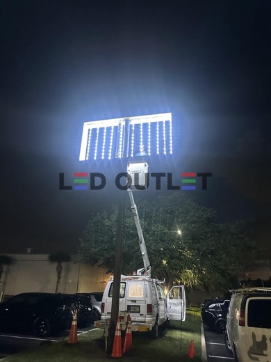 Pylon sign cabinet lit at night with the bucket truck